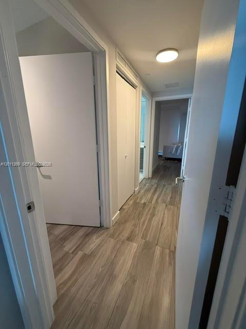 A hallway with light wood-look flooring leads toward a doorway and a closet — 460 NE 28th St # 3408, Miami FL 33137, MIAMI, FL