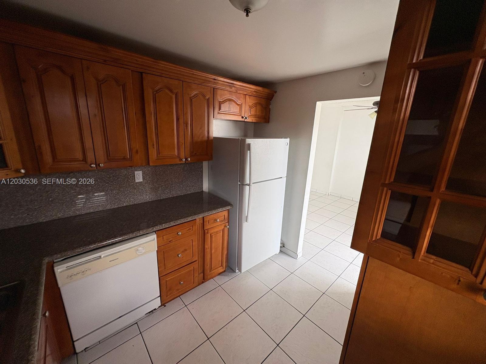 A kitchen features wood cabinets, a white refrigerator, a dishwasher, and tiled flooring — 14185 SW 87th St # 304, Miami FL 33183, MIAMI, FL