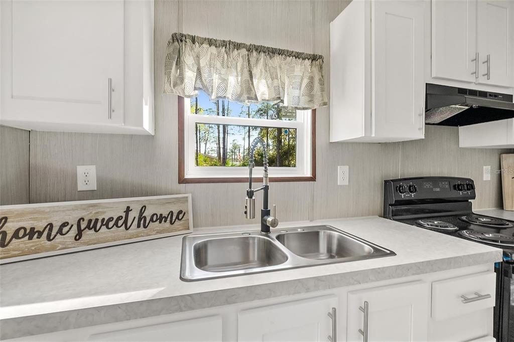 A kitchen features white cabinets, a double stainless steel sink, and a window with valance — 1259 ROSEWOOD STREET, BUNNELL, FL