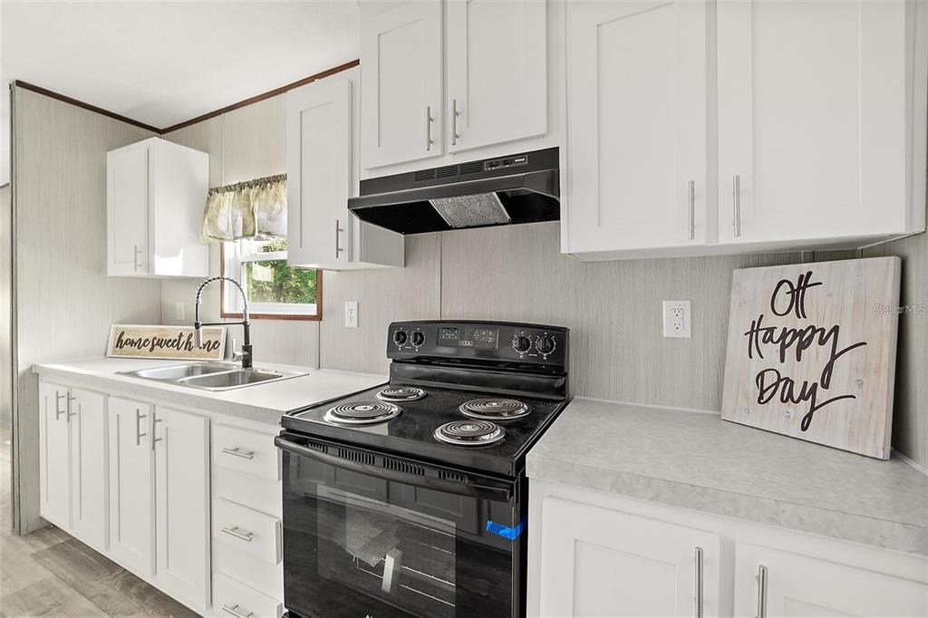 A kitchen features white cabinets, a black electric stove, and light gray countertops — 1259 ROSEWOOD STREET, BUNNELL, FL