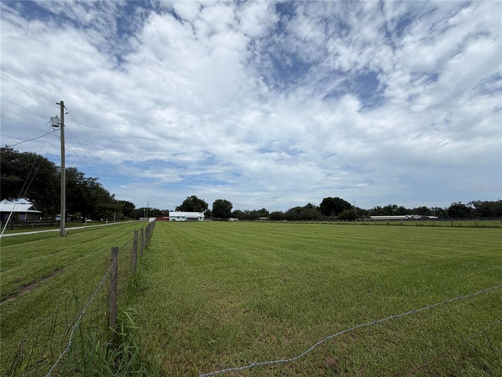 A wide, grassy field is enclosed by a wire fence under a cloudy sky — 4613 KEENE ROAD, PLANT CITY, FL