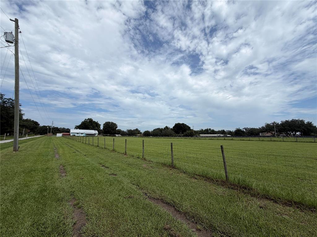 A grassy, fenced-in field under a cloudy sky with a distant house — 4613 KEENE ROAD, PLANT CITY, FL