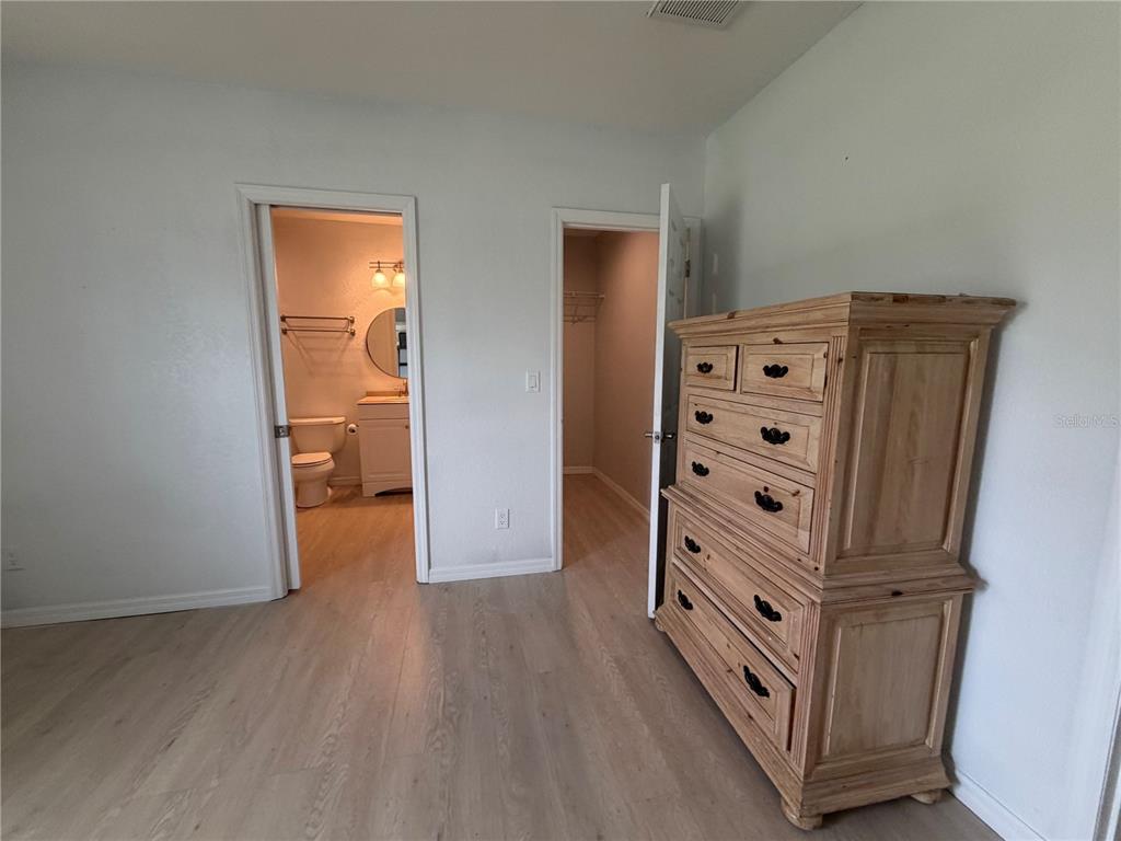 A bedroom features light wood-look flooring, a wooden dresser, and doorways leading to a bathroom and closet — 4613 KEENE ROAD, PLANT CITY, FL