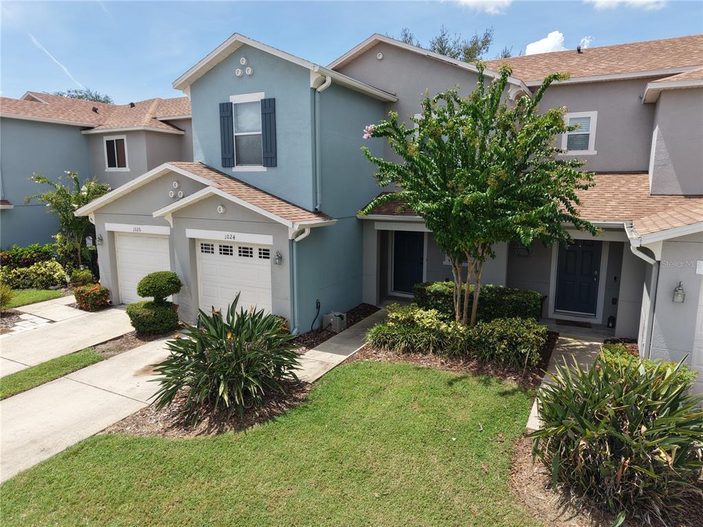 An exterior view of a two-story townhouse with a blue facade and attached garages — 1024 CHALCEDONY STREET, KISSIMMEE, FL