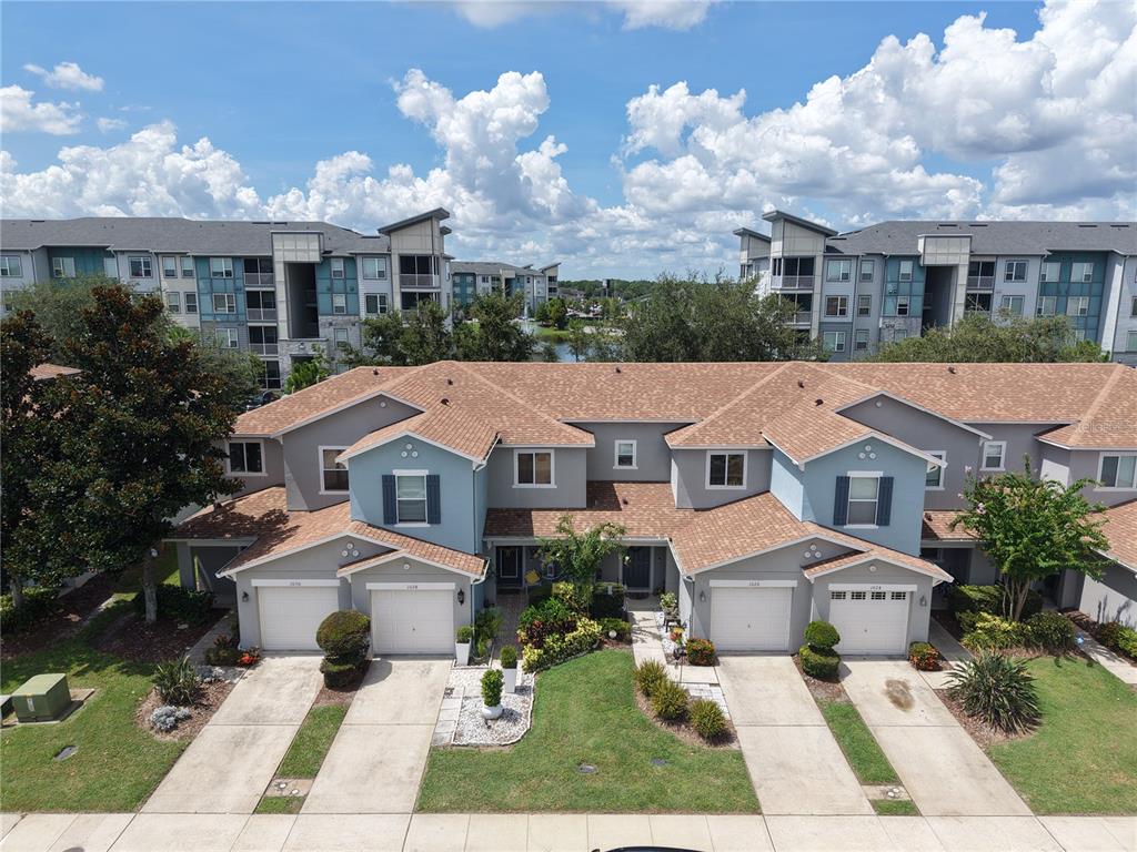 An aerial view shows a two-story townhouse complex with attached garages and a shared driveway — 1024 CHALCEDONY STREET, KISSIMMEE, FL