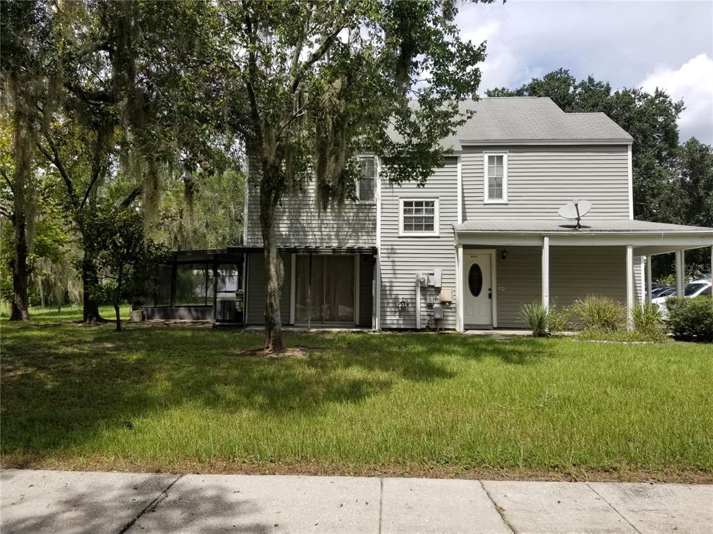 A two-story gray house with a covered porch, sliding glass doors, and a screened patio — 8202 BROWARD PLACE, TEMPLE TERRACE, FL