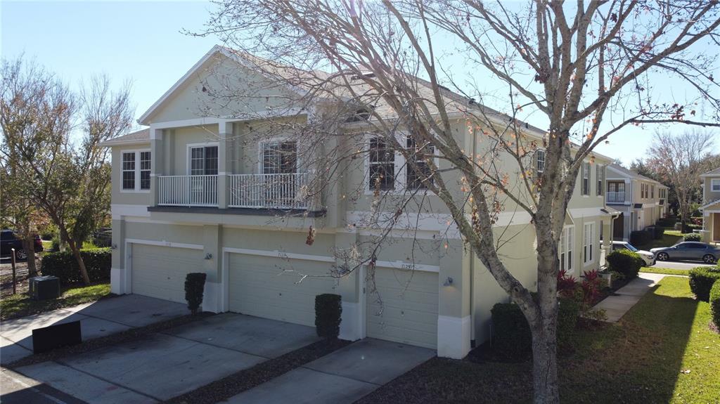 An exterior view of a two-story townhouse with three garage doors and a second-floor balcony — 7125 RED LANTERN DR UNIT 17A, ST CLOUD, FL