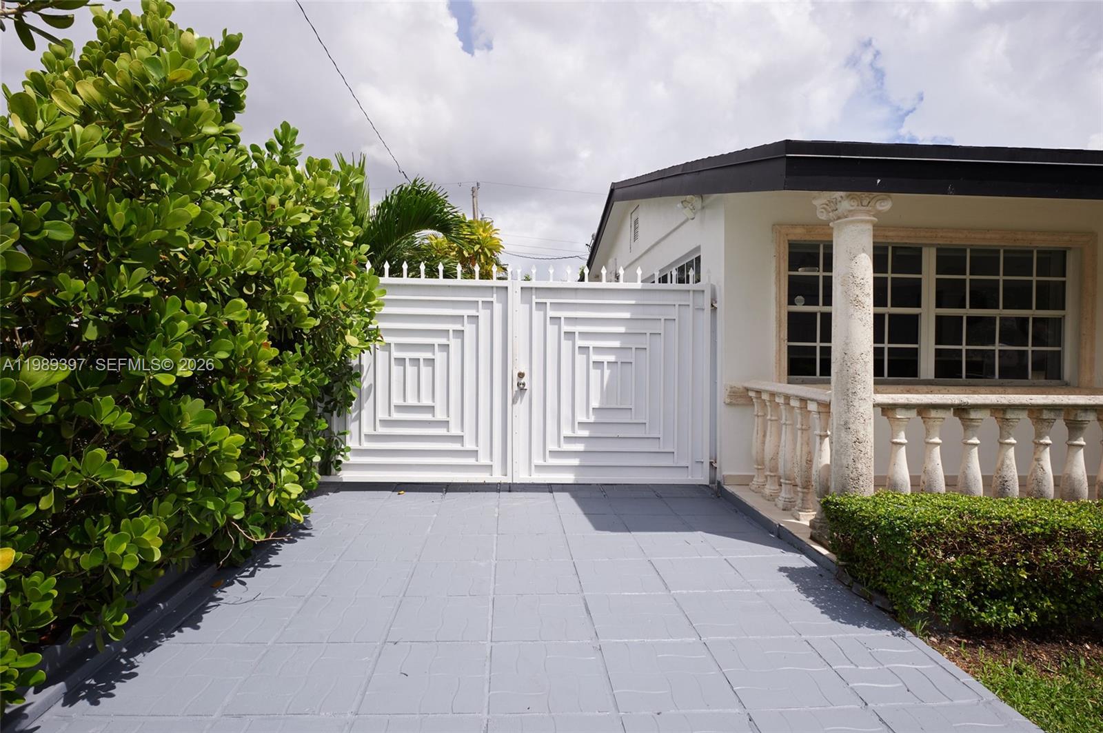 A white metal gate stands at the end of a gray paved driveway — 12293 SW 28th Ter, Miami FL 33175, MIAMI, FL
