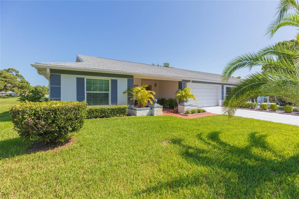 A single-story house with a white garage, gray shutters, and a palm tree in front — 8423 PEBBLE DRIVE, PORT RICHEY, FL