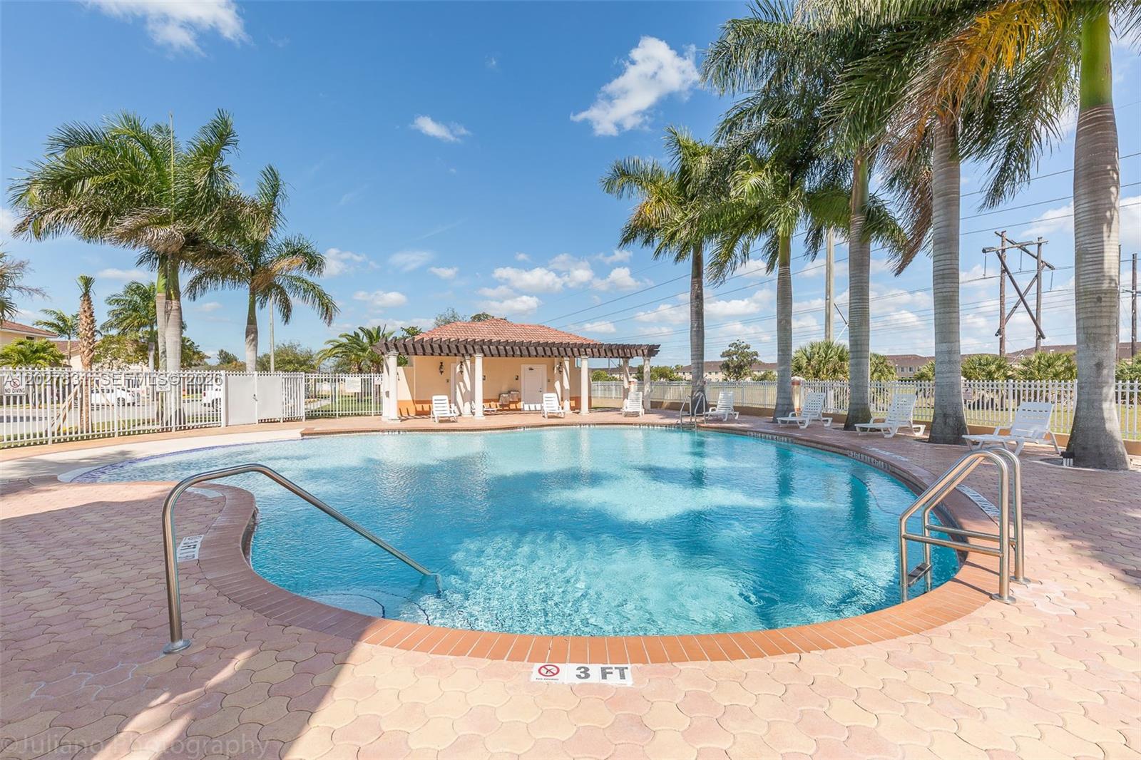 A swimming pool with a surrounding patio and a covered pavilion under a blue sky — 7488 NW 181st St # 7488, Hialeah FL 33015, HIALEAH, FL