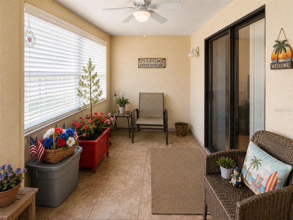 A sunroom features tile flooring, a ceiling fan, wicker furniture, and potted plants — 1126 FAIRVILLA DRIVE UNIT 1126, NEW SMYRNA BEACH, FL