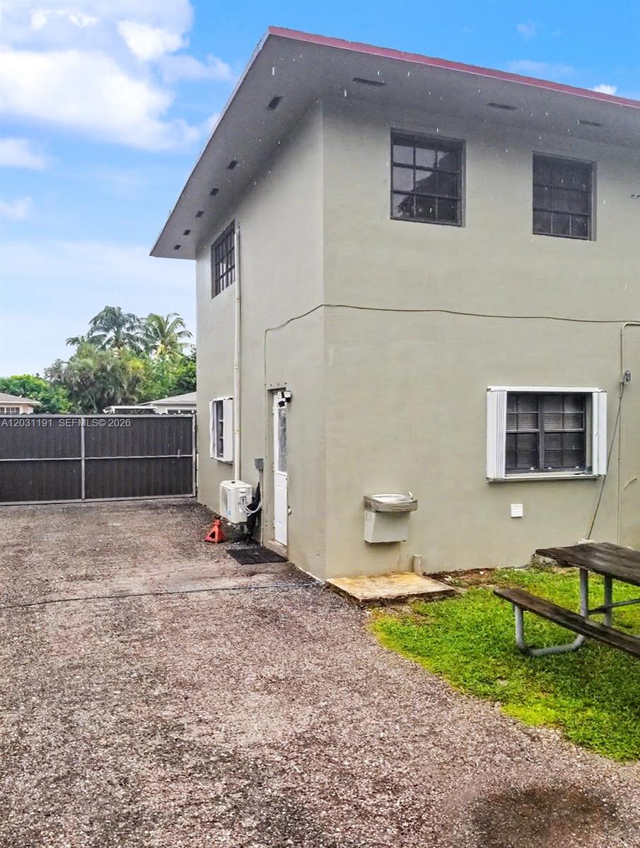 The exterior of a two-story building features a gravel driveway, a water fountain, and windows — 14411 NW 15th Dr, Miami FL 33167, MIAMI, FL