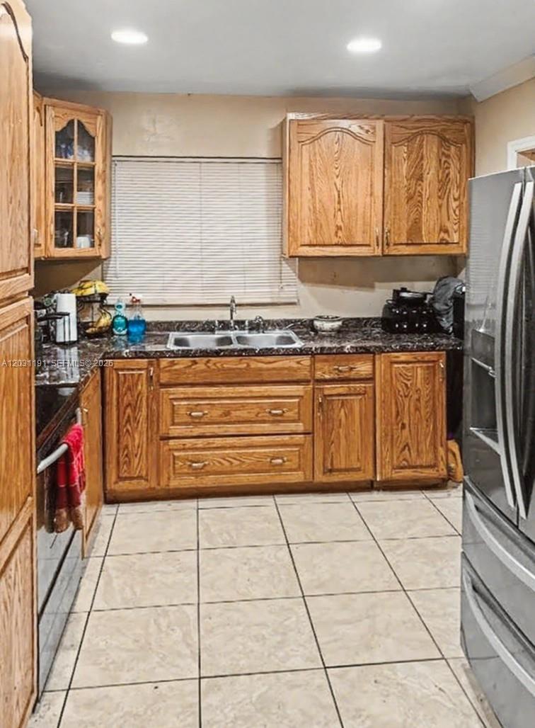 A kitchen features oak cabinets, dark granite countertops, a double sink, and tiled flooring — 14411 NW 15th Dr, Miami FL 33167, MIAMI, FL