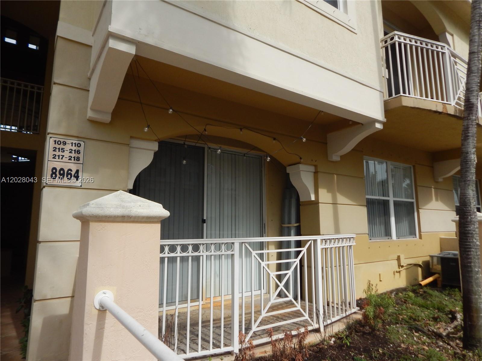 The exterior of a multi-story tan building features a ground-floor patio with white railings — 8964 W Flagler St # 109, Miami FL 33174, MIAMI, FL