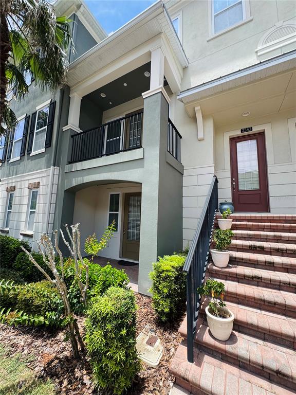 A multi-story townhouse exterior features a covered entryway, a second-floor balcony, and brick stairs — 2583 JOSLIN PLACE, ORLANDO, FL