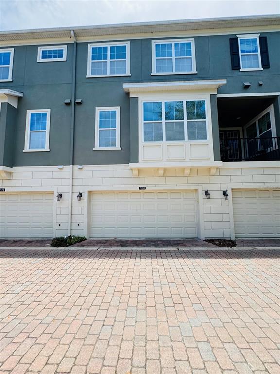 The exterior view shows a multi-story townhouse with three garage doors and a paved driveway — 2583 JOSLIN PLACE, ORLANDO, FL