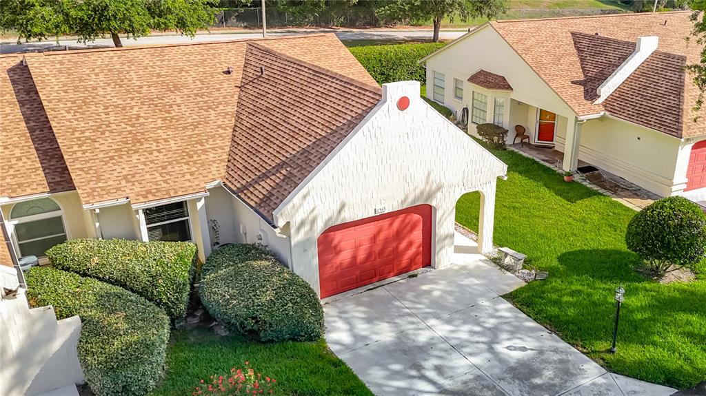 An aerial view shows a house with a red garage door and a brown roof — 11543 ORLEANS LANE, PORT RICHEY, FL