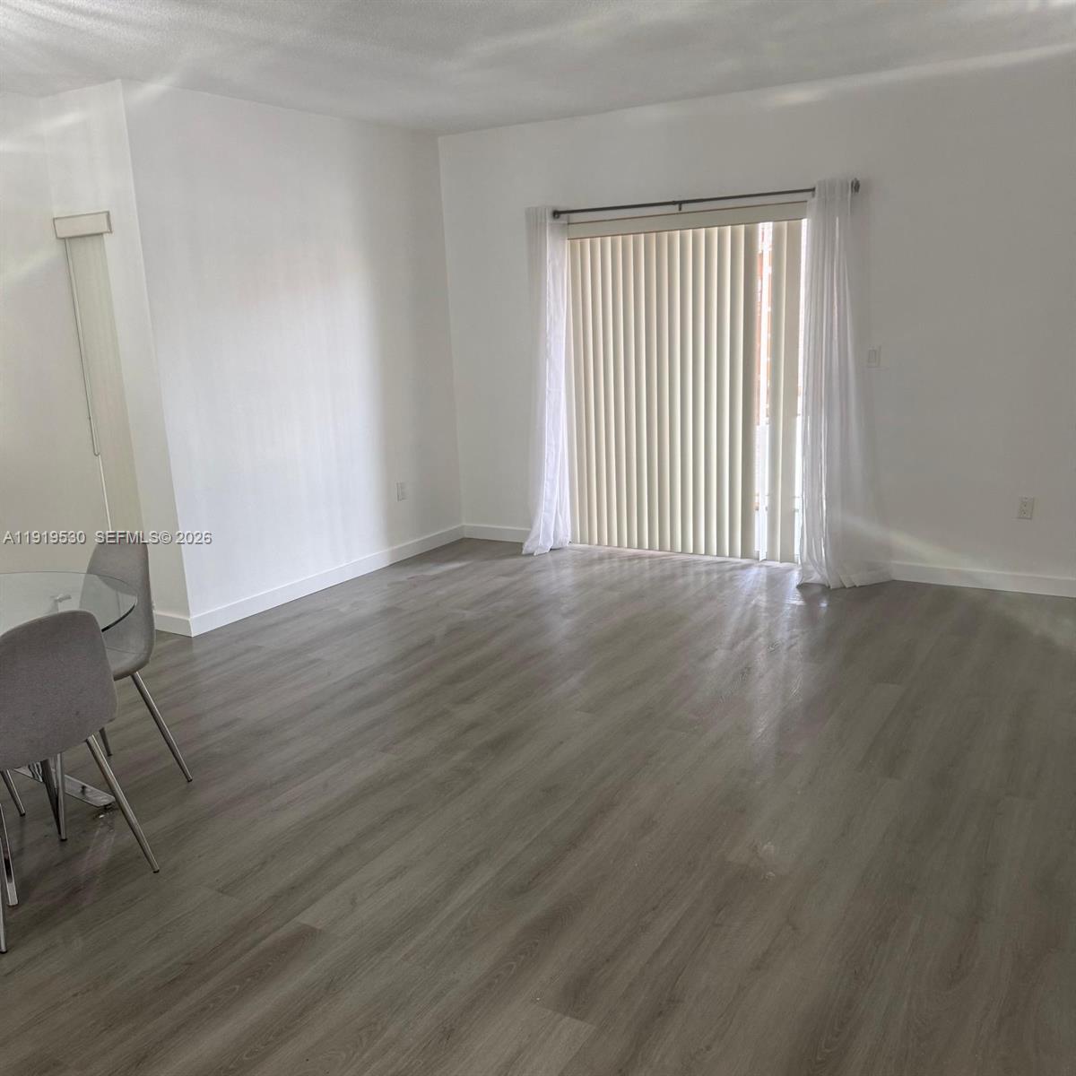 A living room features light gray wood-look flooring, white walls, and a sliding glass door — 9159 SW 77th Ave # 211, Miami FL 33156, MIAMI, FL