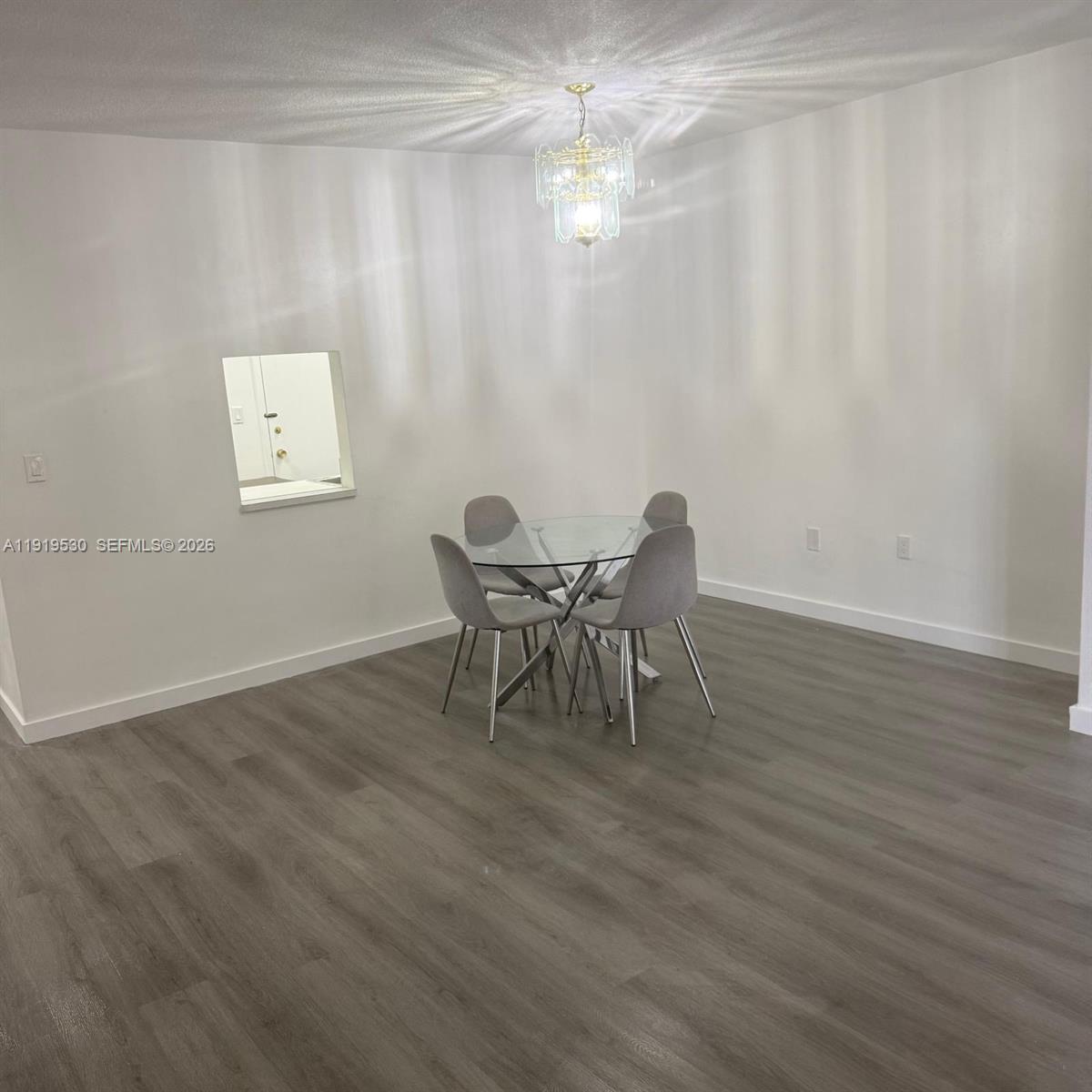 A dining area with a glass table, four gray chairs, and a chandelier on wood-look flooring — 9159 SW 77th Ave # 211, Miami FL 33156, MIAMI, FL