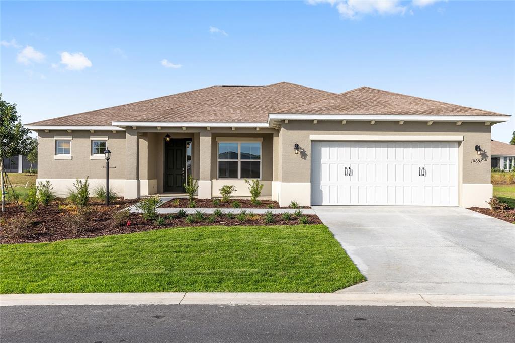A single-story house with a tan stucco exterior, a brown shingled roof, and a garage — 10657 SW 102ND LANE, OCALA, FL