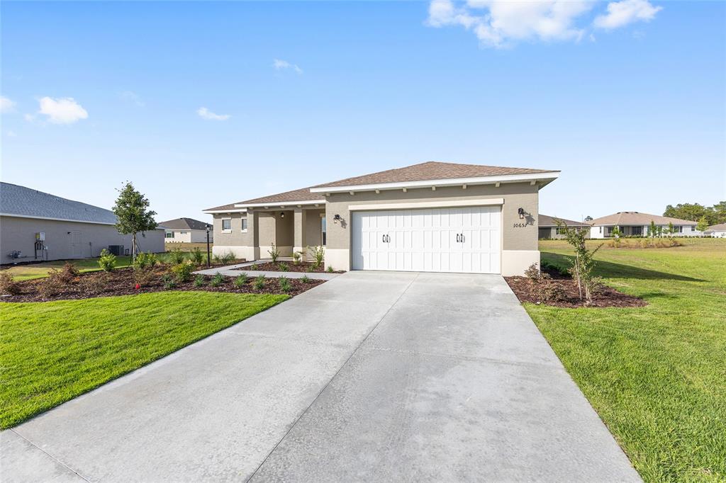 A single-story house with a two-car garage, concrete driveway, and landscaped front yard — 10657 SW 102ND LANE, OCALA, FL