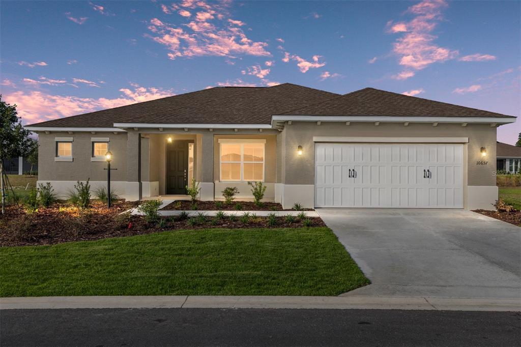 A single-story house with a beige stucco exterior, a two-car garage, and a brown roof — 10657 SW 102ND LANE, OCALA, FL