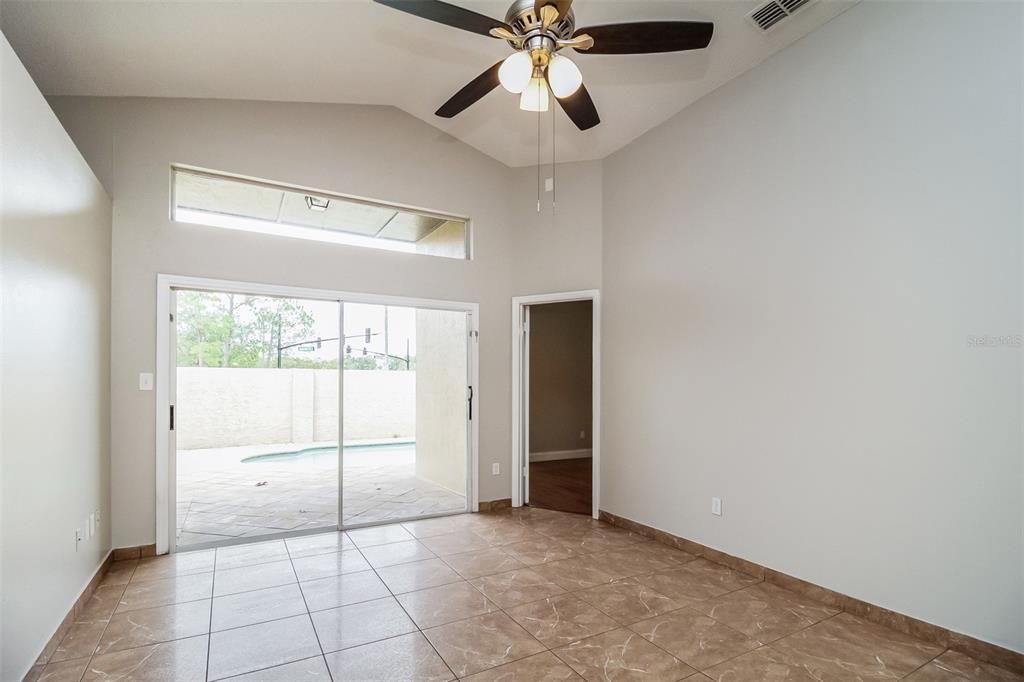 A room with tiled floors, a vaulted ceiling, a ceiling fan, and sliding glass doors — 120 LAKEBREEZE CIRCLE, LAKE MARY, FL