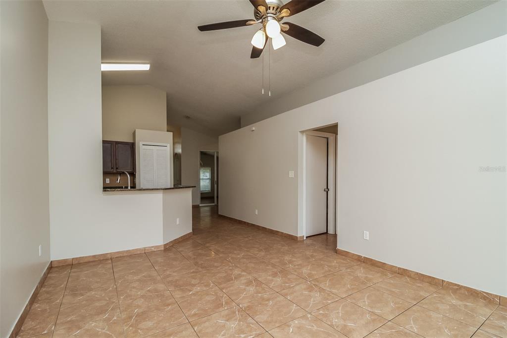 An open living area features tan tile flooring, white walls, and a ceiling fan — 120 LAKEBREEZE CIRCLE, LAKE MARY, FL