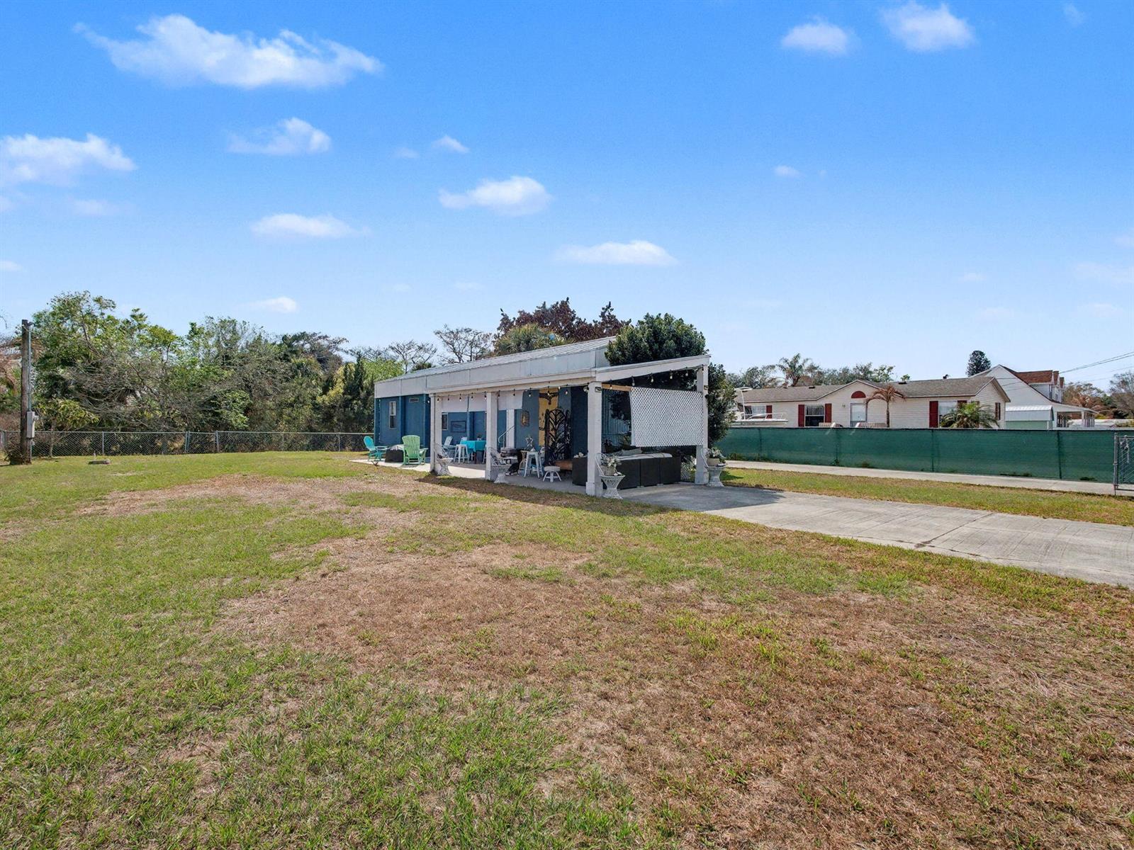 A blue house with a covered patio sits on a large, grassy lot — 4024 SE 29th Court, Okeechobee FL 34974, OKEECHOBEE, FL
