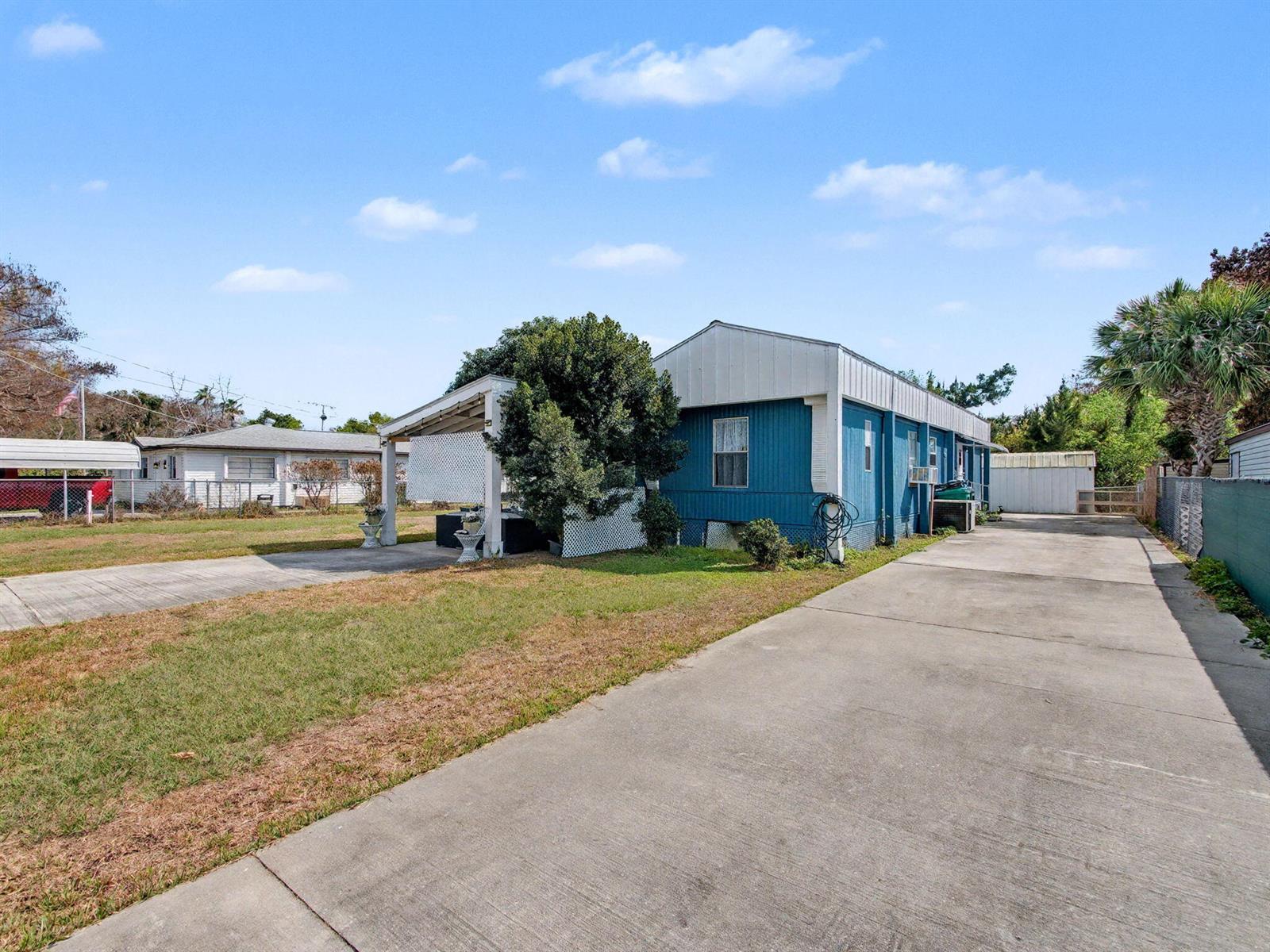 A blue mobile home with a carport sits on a lot with a concrete driveway — 4024 SE 29th Court, Okeechobee FL 34974, OKEECHOBEE, FL