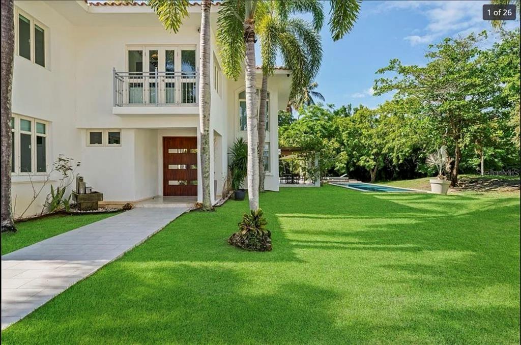 A white two-story house with a wooden front door, balcony, and a backyard swimming pool — 121 DORADO BEACH EAST, DORADO, PR