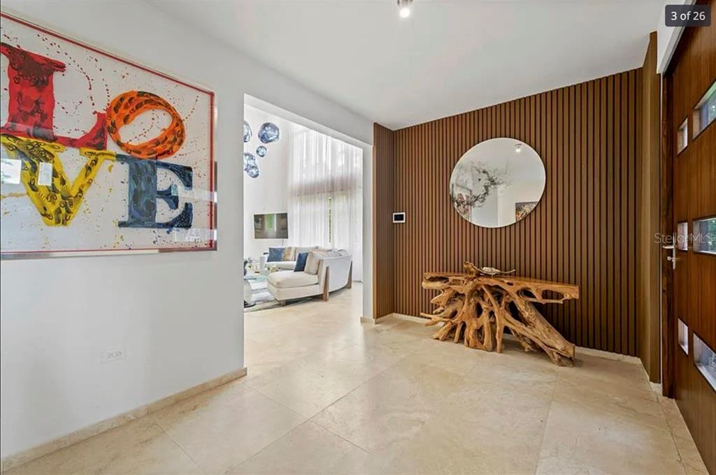 An entryway features a wood-slatted wall, a root-style console table, and a large art piece — 121 DORADO BEACH EAST, DORADO, PR