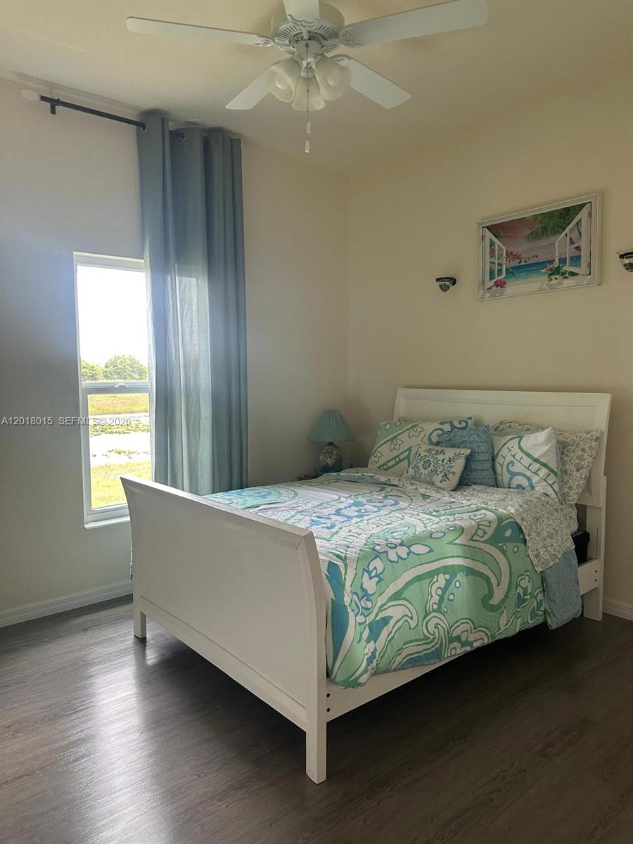 A bedroom features a white bed, a ceiling fan, and a window with blue curtains — 9020 W MAC CT, La Belle FL 33935, LA BELLE, FL