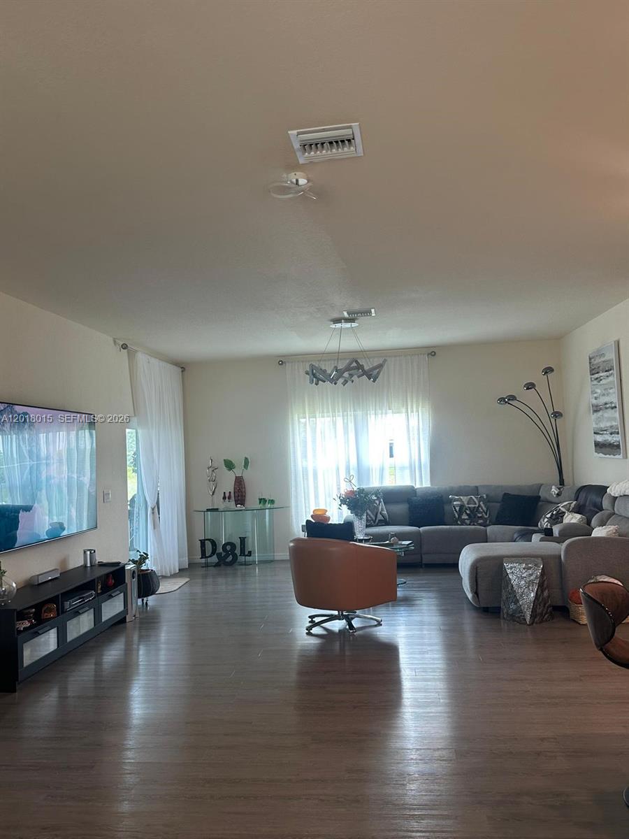 A living room features a sectional sofa, a television, and wood-look flooring — 9020 W MAC CT, La Belle FL 33935, LA BELLE, FL