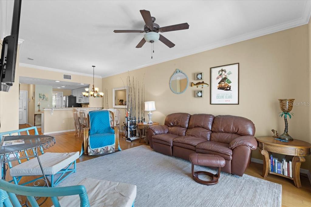 A living room features a brown leather sofa, a blue armchair, and a ceiling fan — 54 SE 910TH AVENUE UNIT 115, SUWANNEE, FL