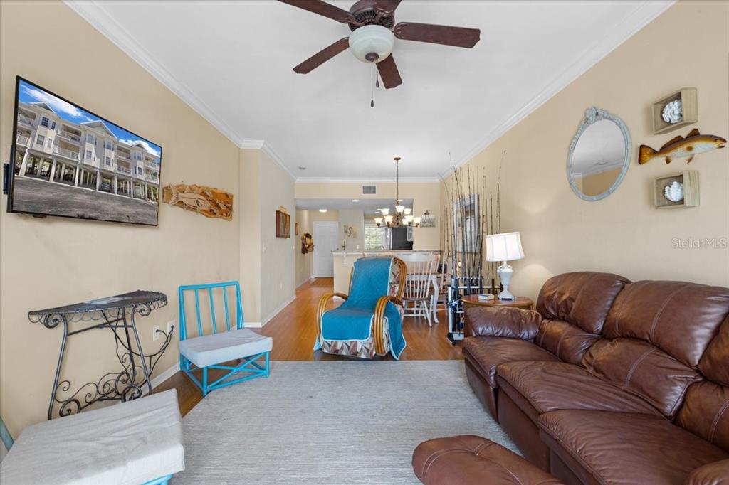 A living room features a brown leather sofa, a blue accent chair, and a television — 54 SE 910TH AVENUE UNIT 115, SUWANNEE, FL
