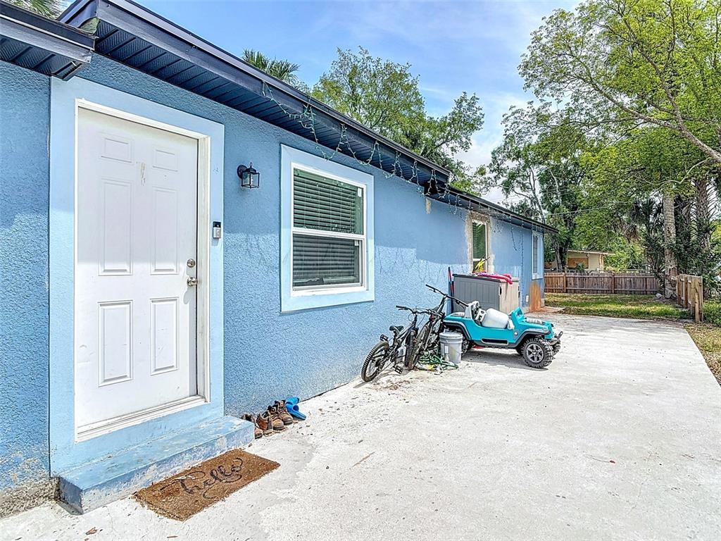 A blue exterior wall features a white door, a window, and a small toy vehicle — 1403 W 13TH PLACE, SANFORD, FL