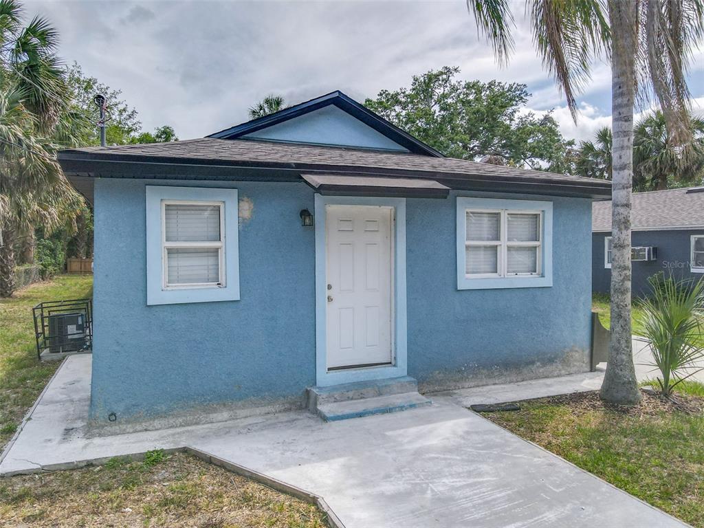 A small, blue, single-story house with a white front door and a concrete walkway — 1403 W 13TH PLACE, SANFORD, FL