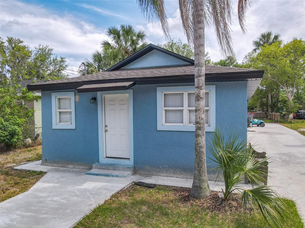 A small, blue, single-story house with a white door and a concrete driveway — 1403 W 13TH PLACE, SANFORD, FL