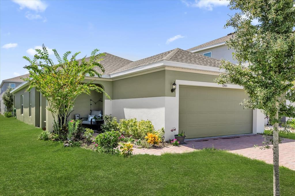 A single-story house with a two-tone exterior, a garage, and a small covered patio area — 6985 WILSON PASTURE AVENUE, GROVELAND, FL