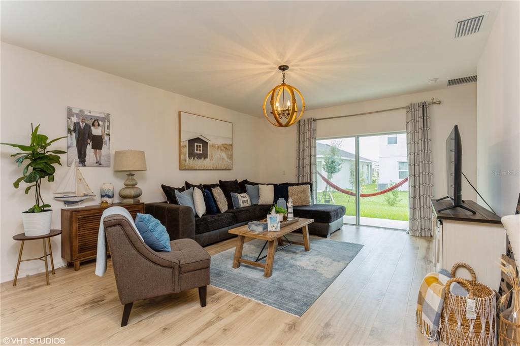 A living room features a sectional sofa, wooden coffee table, and a globe-style chandelier — 6985 WILSON PASTURE AVENUE, GROVELAND, FL