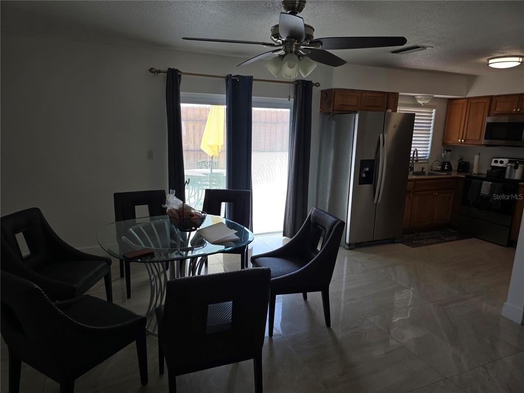 A dining area with a glass table and chairs sits adjacent to a kitchen — 537 MELODY CIRCLE, SARASOTA, FL