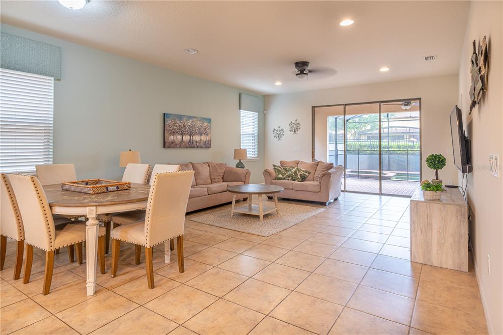 An open-concept living and dining area features tile flooring, neutral furniture, and sliding glass doors — 1888 GOBI DRIVE, KISSIMMEE, FL