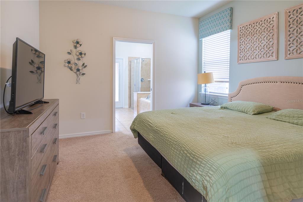 A bedroom features a bed with a light green quilt, a dresser, and an attached bathroom — 1888 GOBI DRIVE, KISSIMMEE, FL