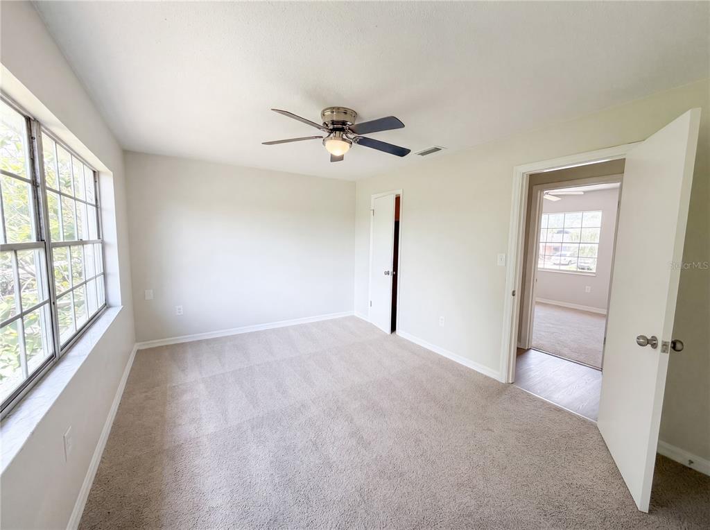 A bedroom with beige carpet, a ceiling fan, and a doorway leading to another room — 333 E CHELSEA STREET, DELAND, FL