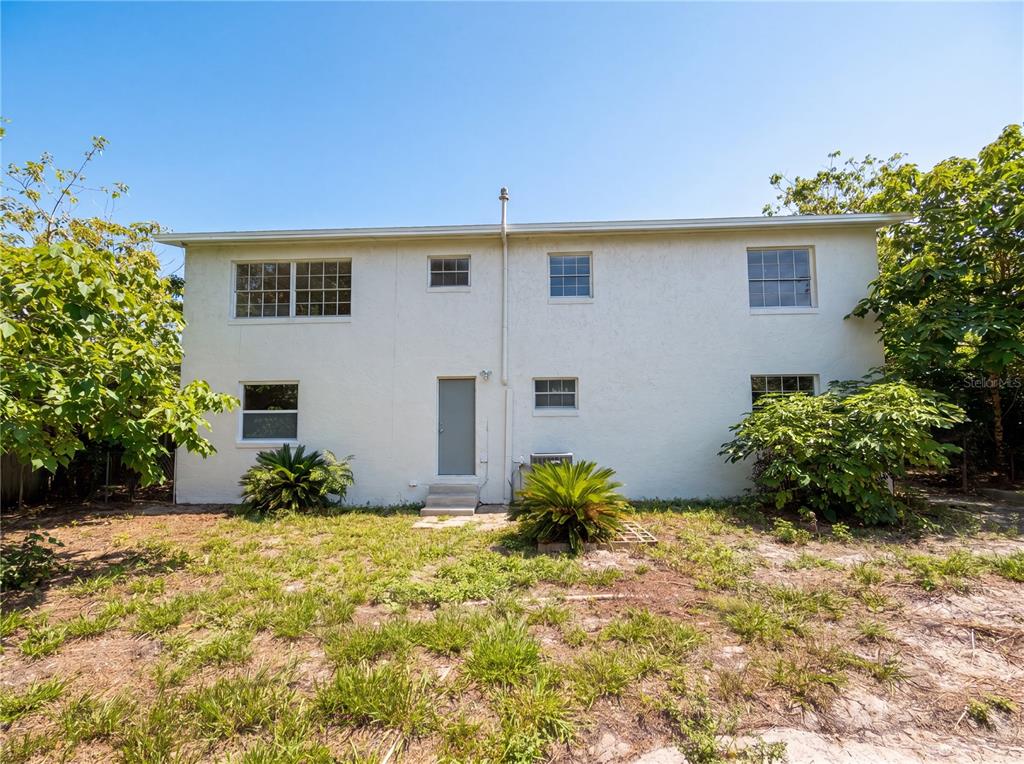 The rear exterior of a two-story white stucco house features several windows and a door — 333 E CHELSEA STREET, DELAND, FL