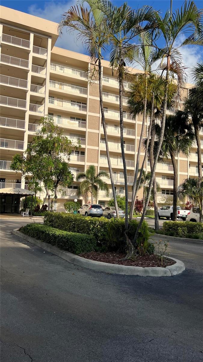 A multi-story apartment building with balconies stands behind a landscaped parking area with palm trees — 2901 S Palm Aire Dr # 408, Pompano Beach FL 33069, POMPANO BEACH, FL