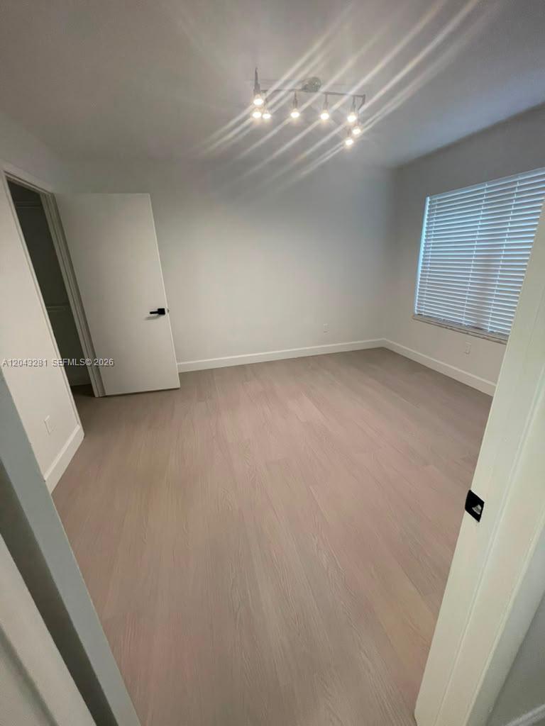 An empty bedroom features light-colored wood flooring, white walls, and a modern ceiling light fixture — 4341 W Mcnab Rd # 21, Pompano Beach FL 33069, POMPANO BEACH, FL