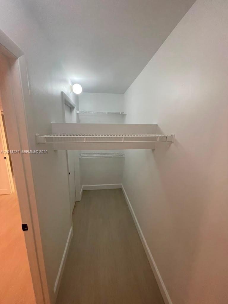 A narrow walk-in closet features white walls, light wood-look flooring, and wire shelving — 4341 W Mcnab Rd # 21, Pompano Beach FL 33069, POMPANO BEACH, FL