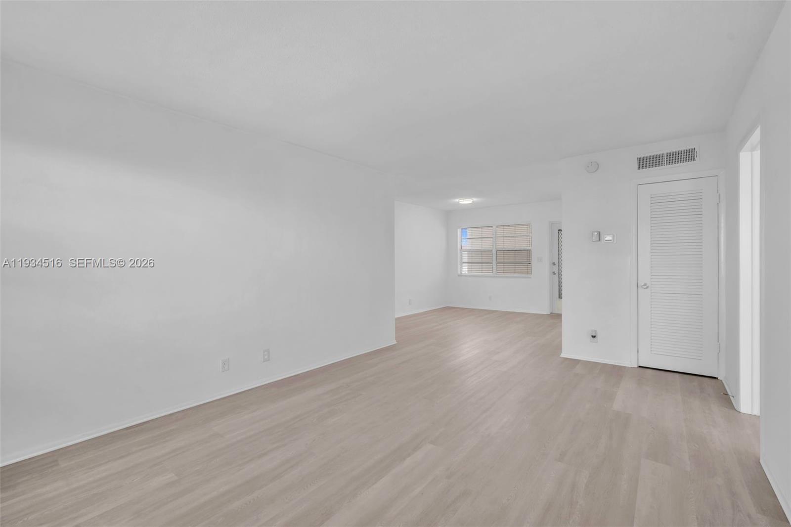 An empty room with white walls and light wood-look flooring features a white louvered door — 1280 NW 43rd Ave # 302, Lauderhill FL 33313, LAUDERHILL, FL